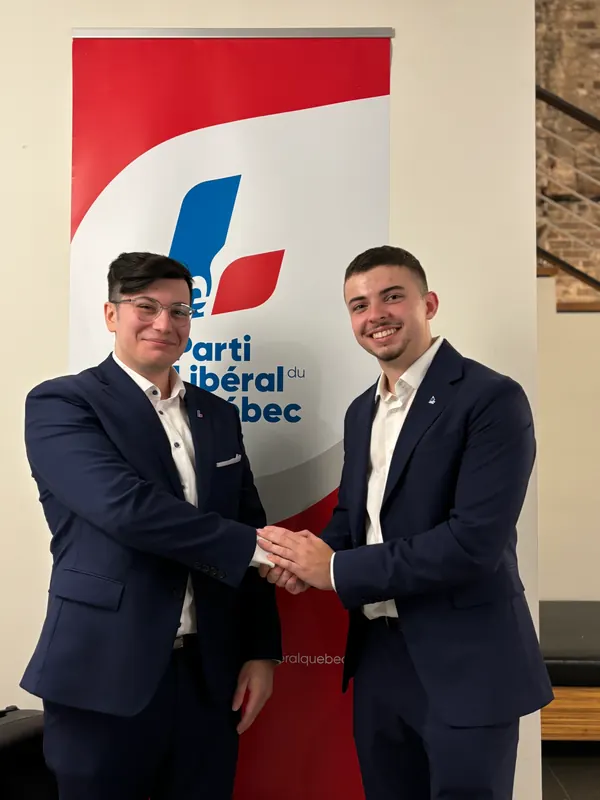 Bruno Chieco échange avec John Panatierre devant une bannière du Parti libéral du Québec.